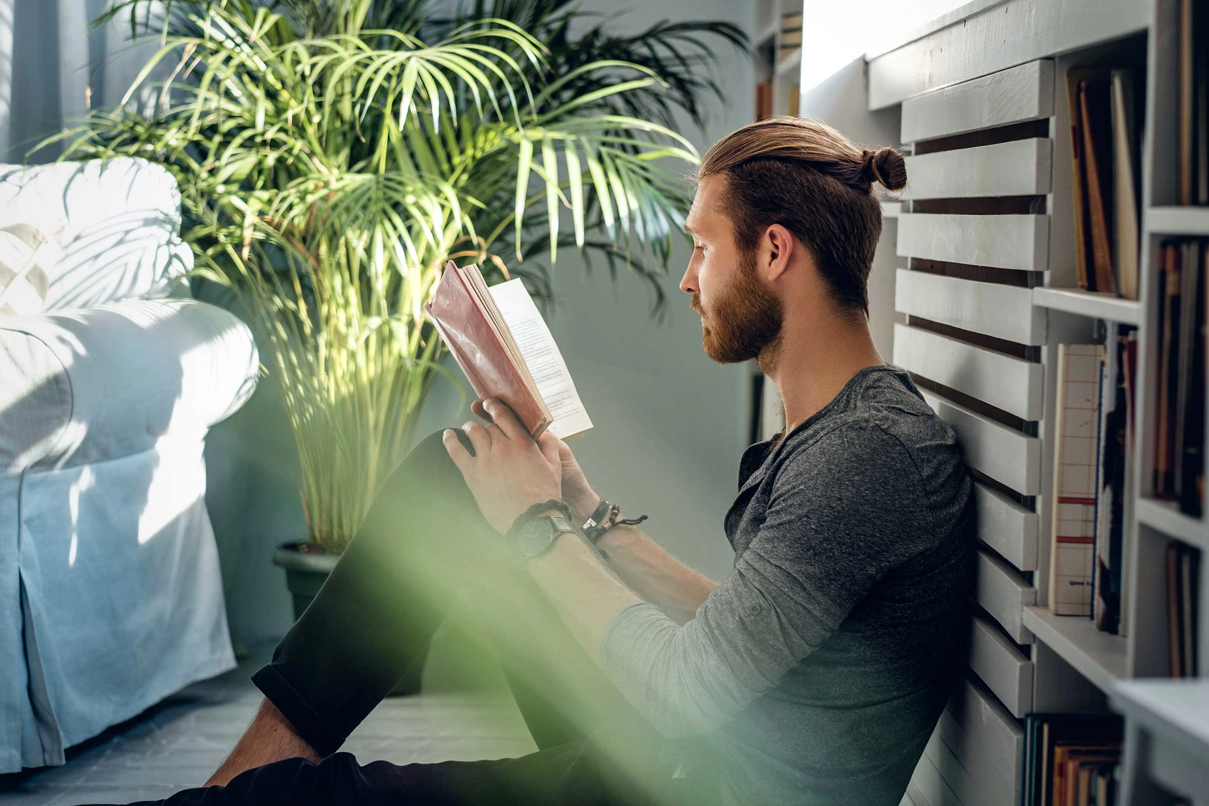 Man sat with back against the wall reading a book